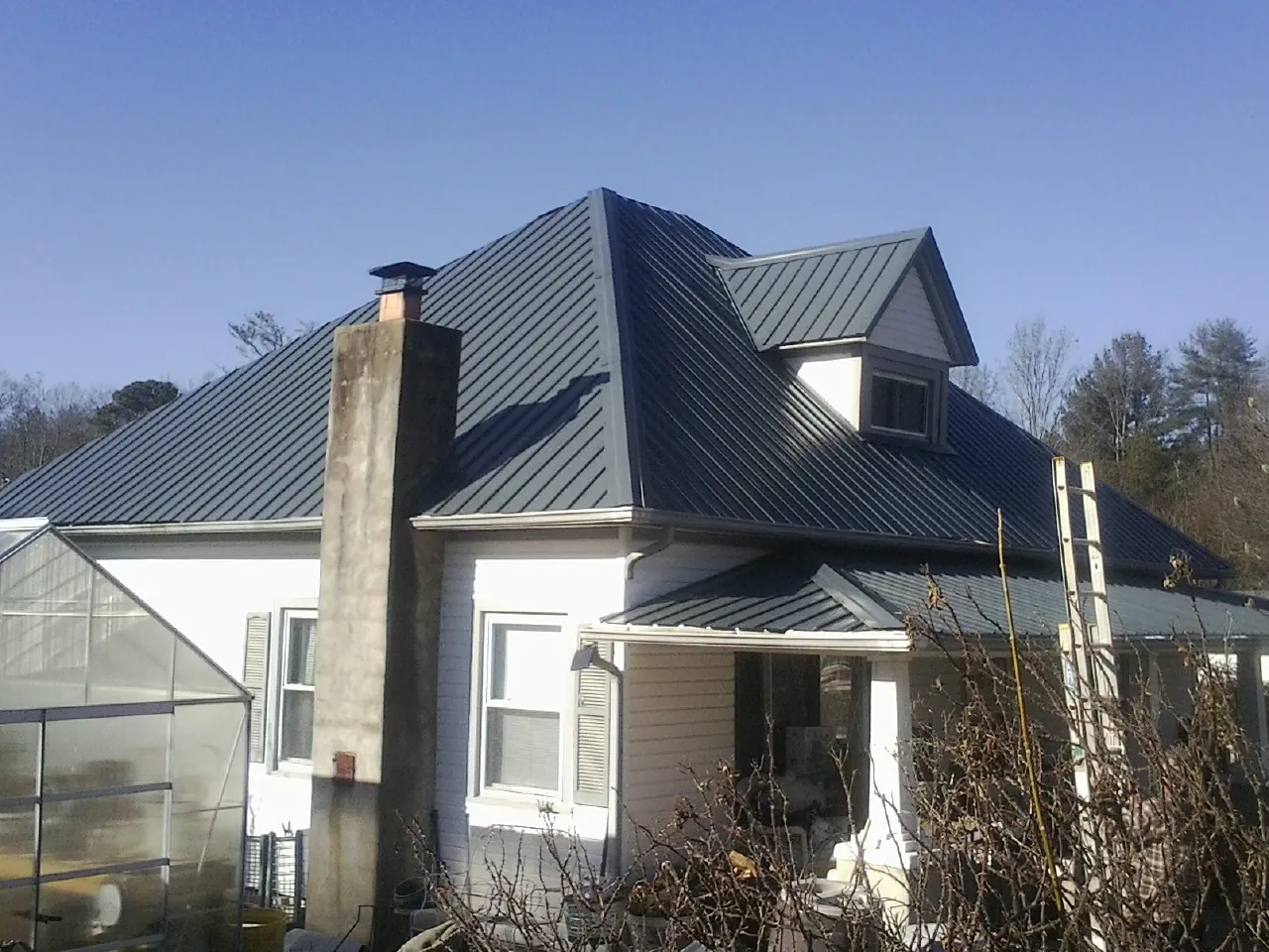 Dark blue standing seam metal roof on a white farmhouse with dormer — Slate & Tile Roof Repair by Roofing Brothers in La Canada Flintridge