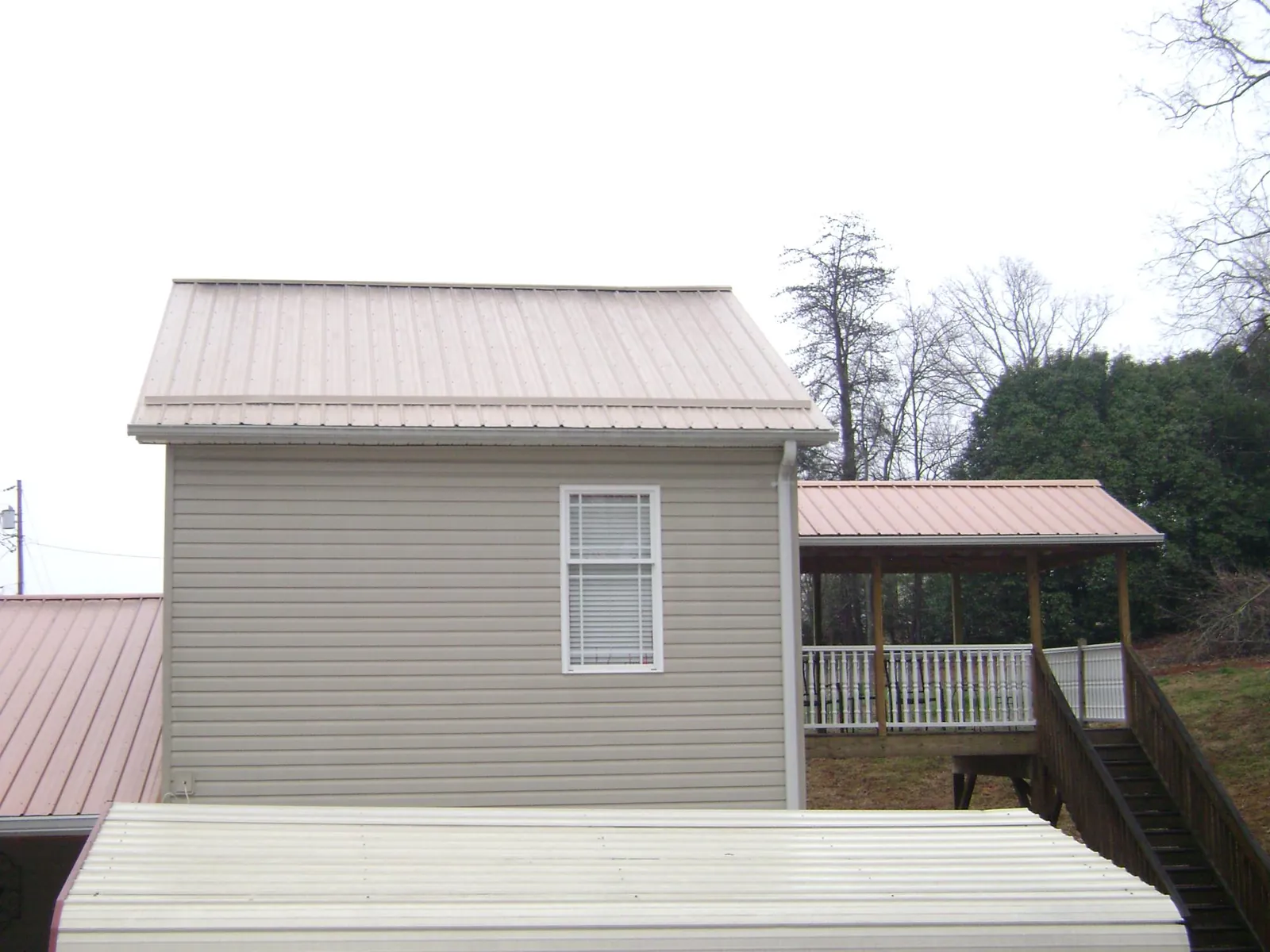 Tan metal roofs on a two story addition and attached porch, from a Roof Replacement job in La Canada Flintridge